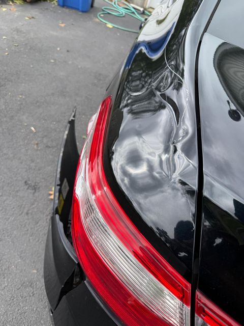 Crease with cracked paint high on the quarter panel beside the trunk lid